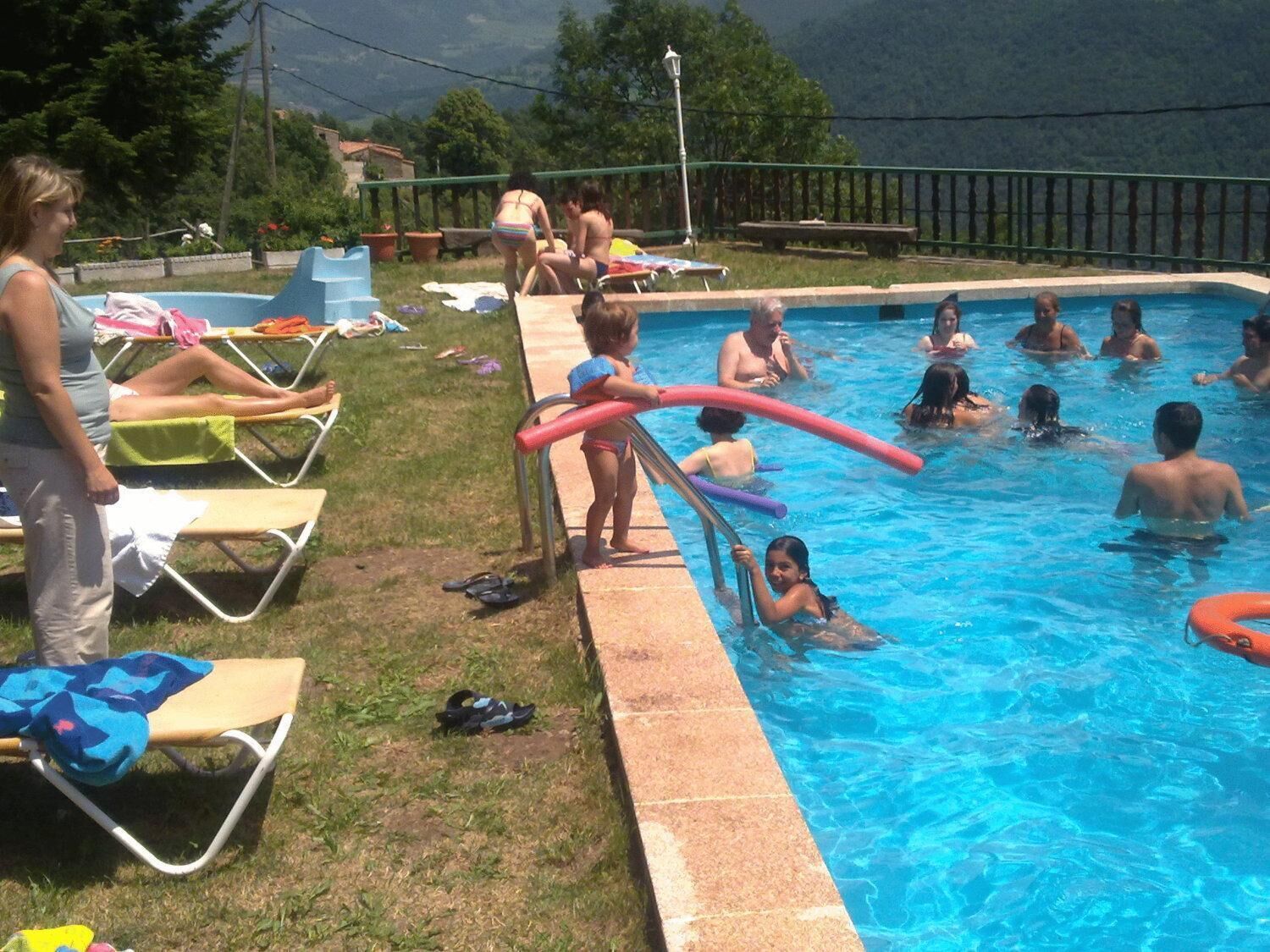 Une piscine avec des personnes dans l’eau et au bord de la piscine.