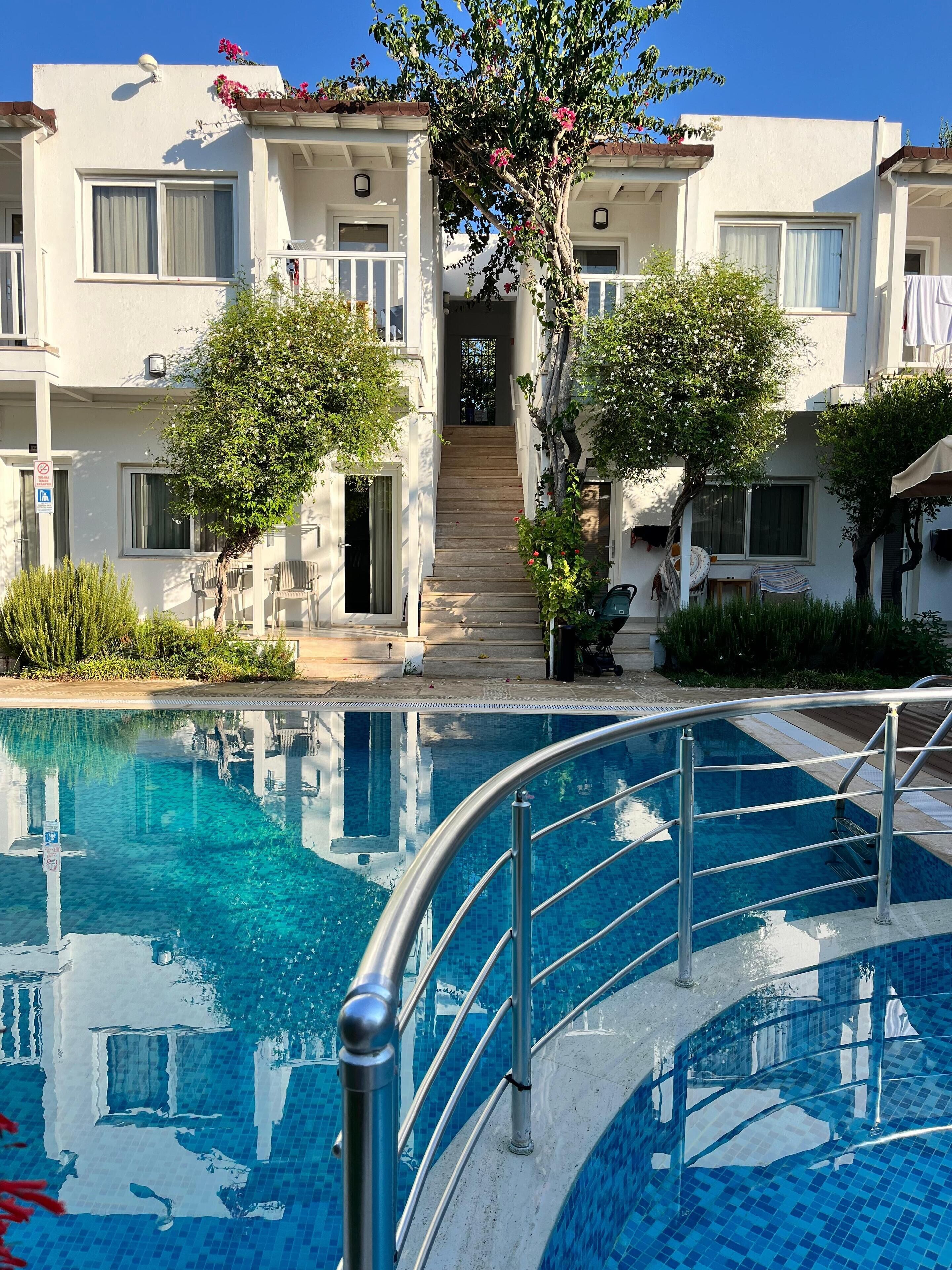 Una piscina al aire libre, sombrillas, sillones reclinables de piscina
