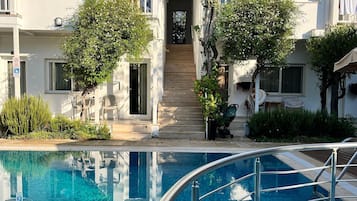 Una piscina al aire libre, sombrillas, sillones reclinables de piscina