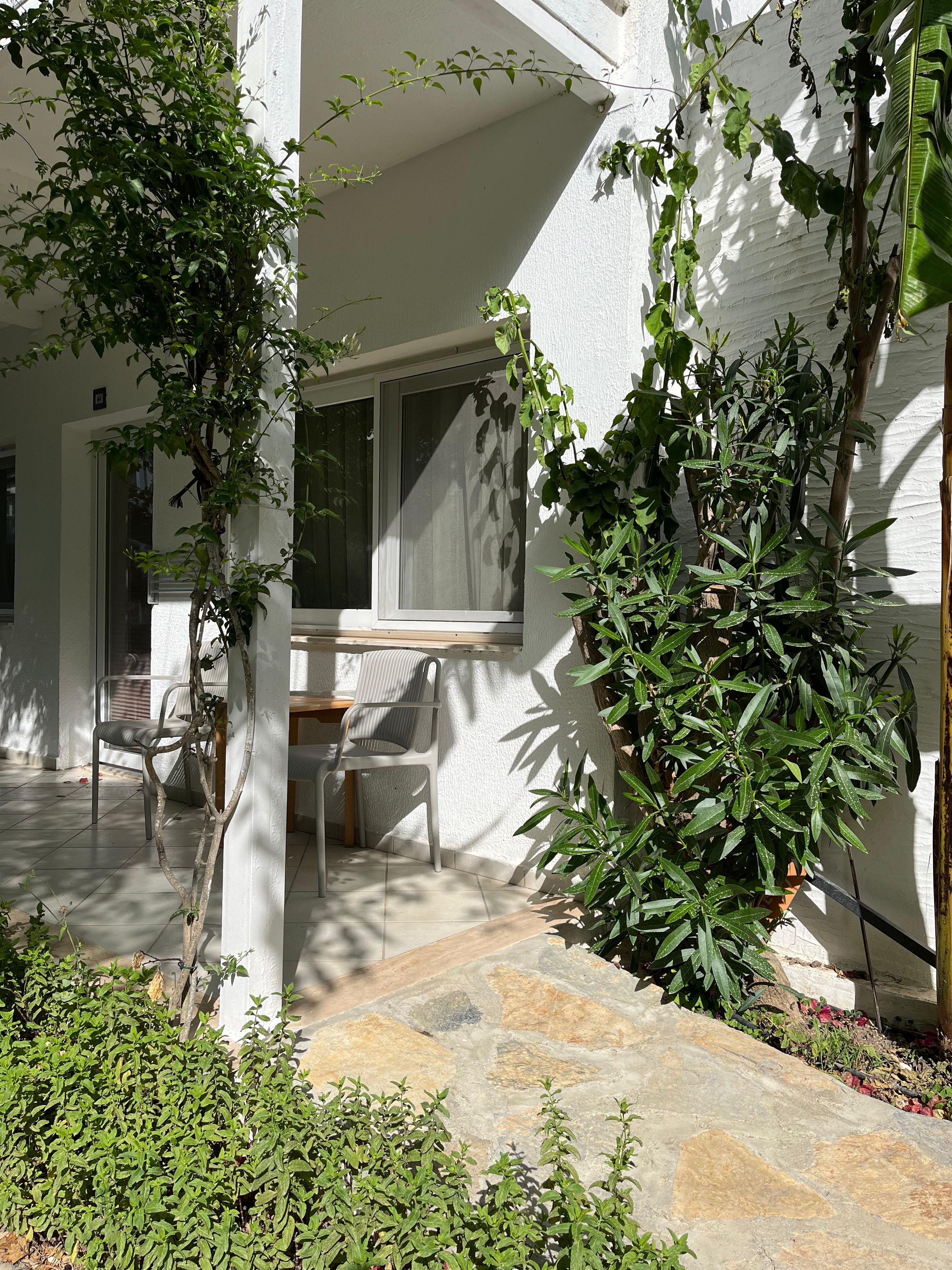 Una zona patio con un muro bianco, una finestra e un tavolo con sedie.