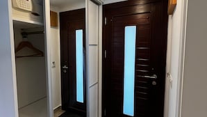A hallway with a sliding glass door closet, a wooden door with a window, and a small rug at the entrance. - Hotel Gumusluk (Bodrum)
