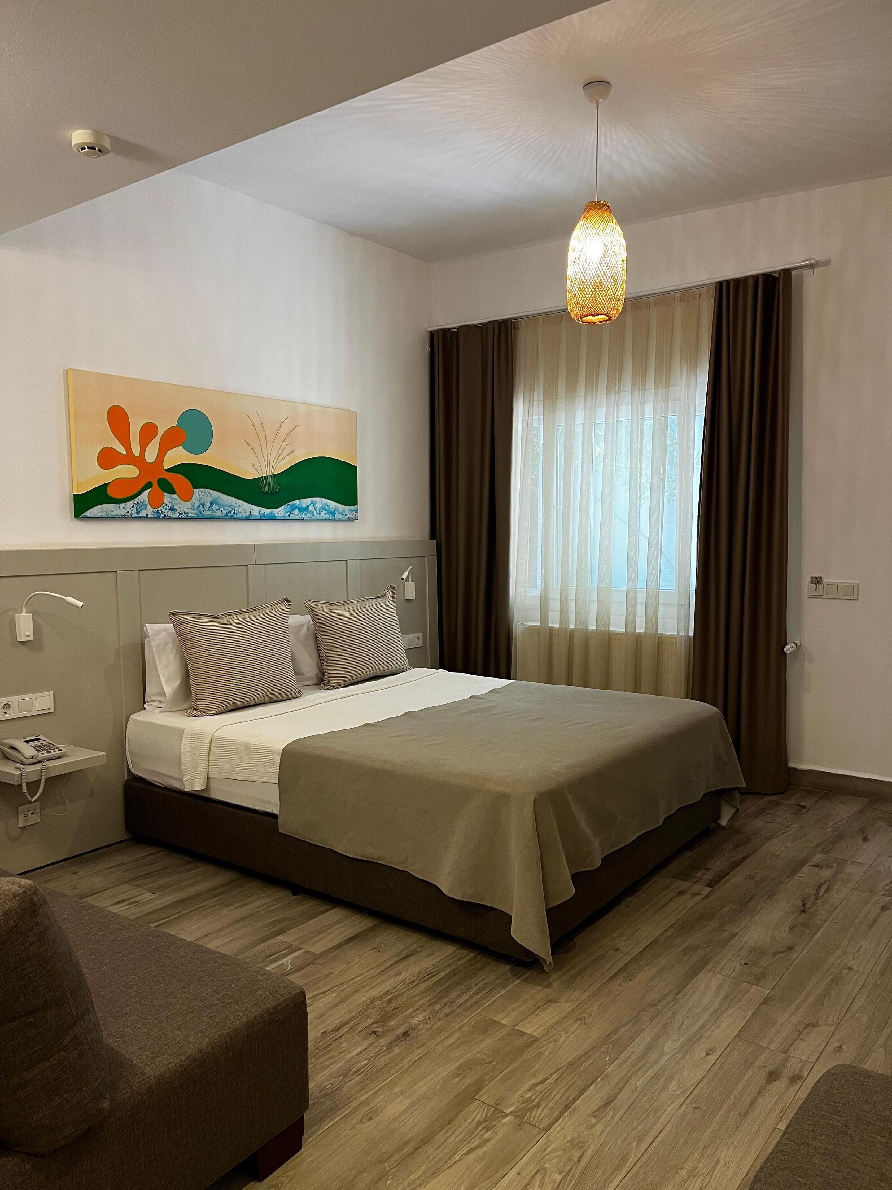 Quarto moderno com uma cama grande, telefone de cabeceira, abajur e um quadro na parede.