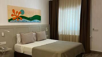 Quarto moderno com uma cama grande, telefone de cabeceira, abajur e um quadro na parede.