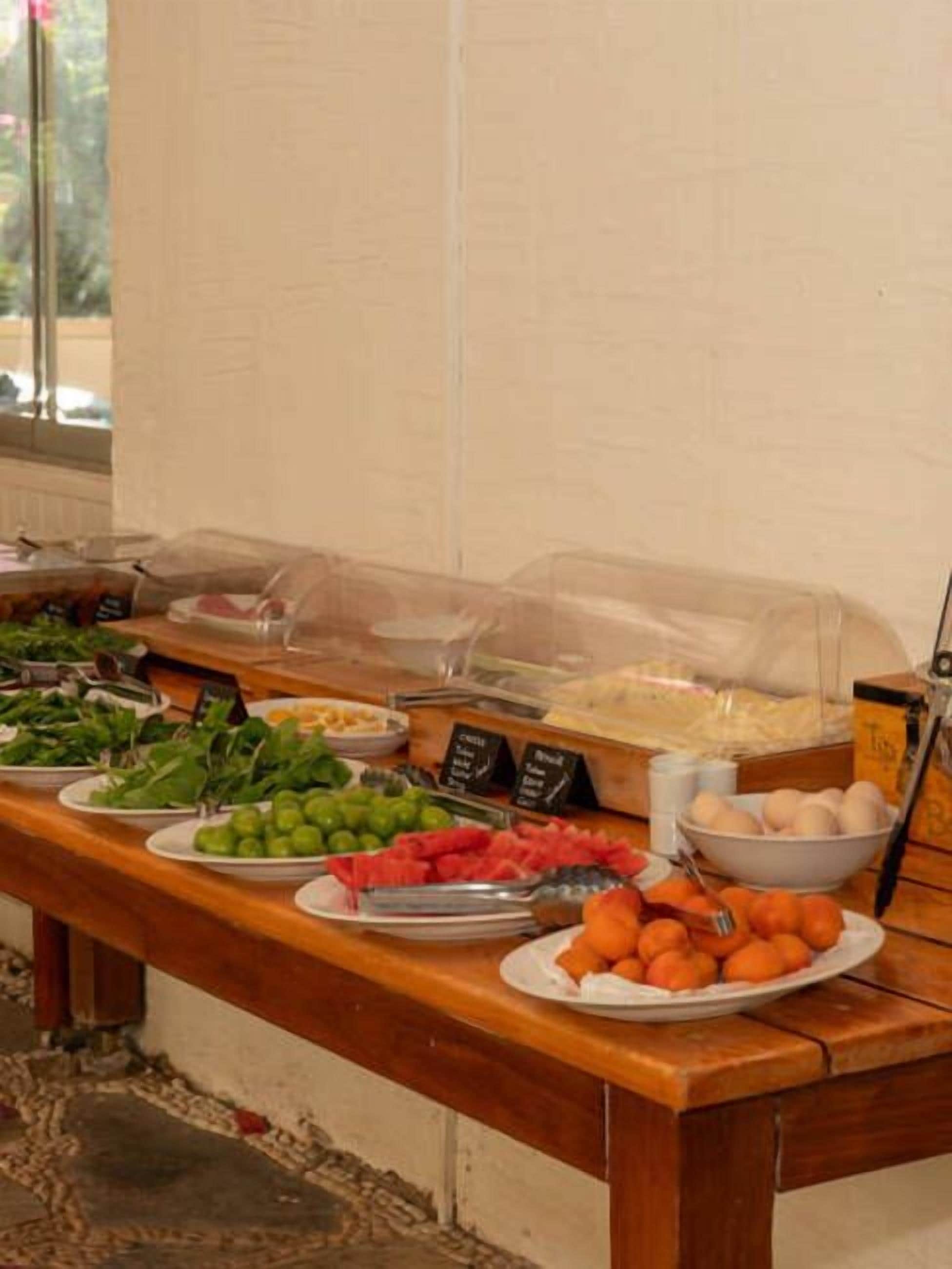 Une table de buffet proposant divers aliments, notamment des fruits, des légumes et des œufs.