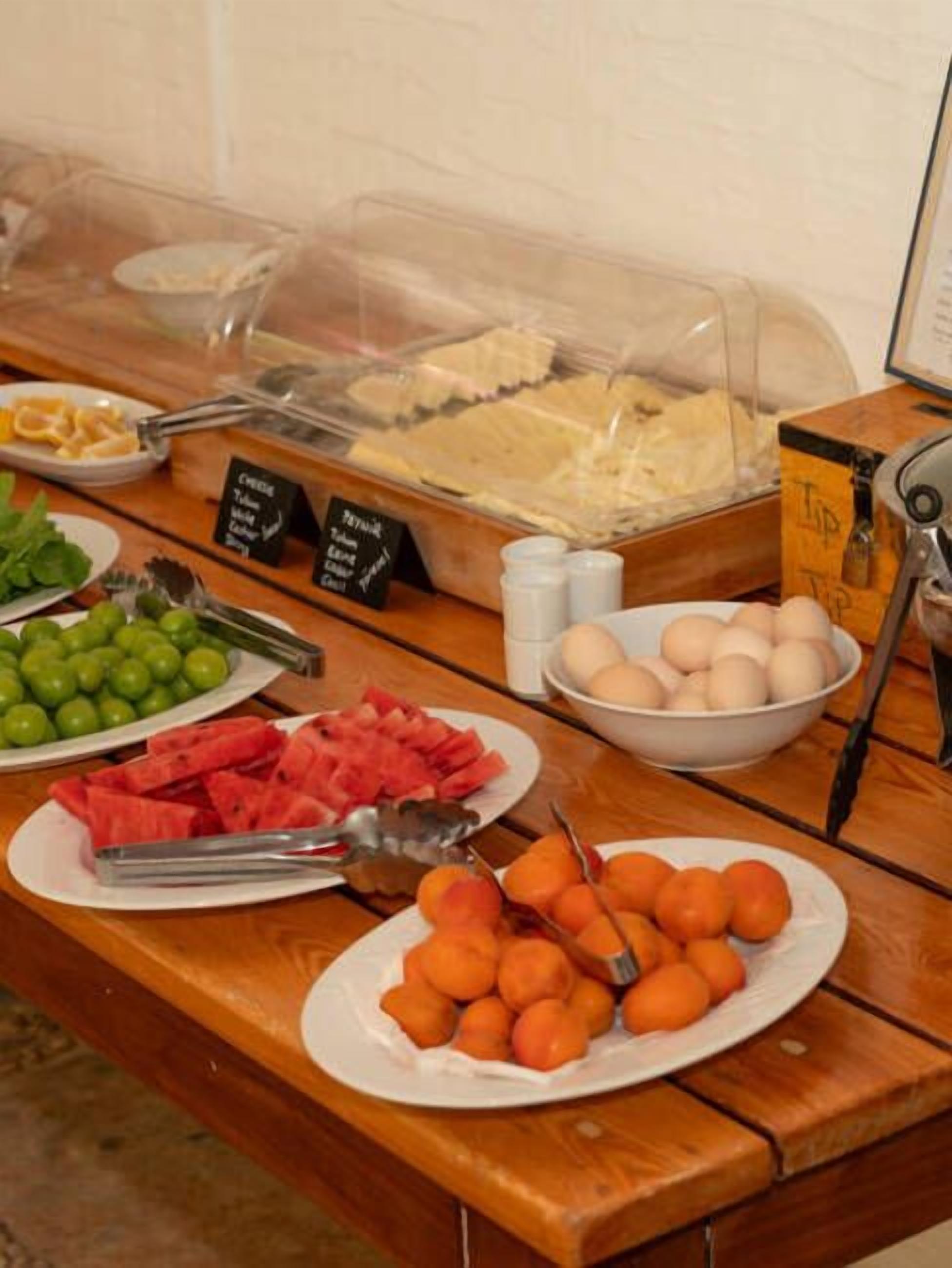 A buffet table with various food items including fruits, vegetables, and eggs.