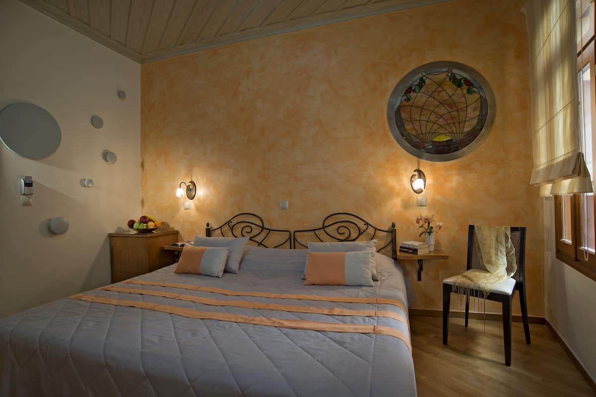 A bedroom with a bed, a chair, a nightstand, a wall clock, and a decorative circular window.