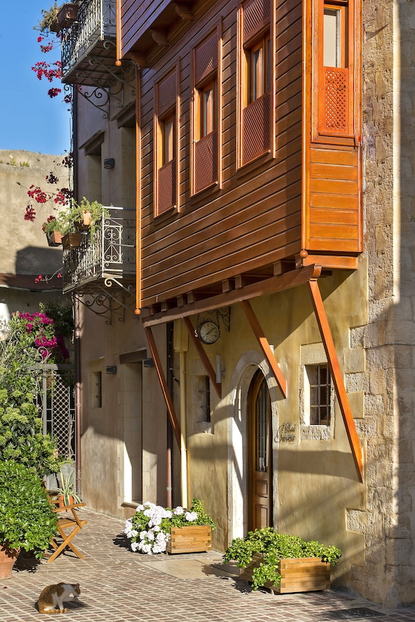 Un edificio tradicional con balcones de madera, un muro de piedra y plantas en macetas.