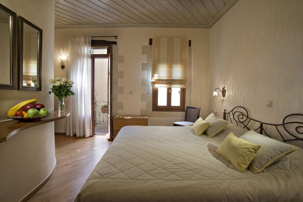 A bedroom with a large bed, bedside tables, a mirror, and a fruit bowl.