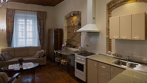 A compact kitchen with a dining area, a built-in oven, and a stone wall backsplash. - Bernardinu B&B House (Vilnius)