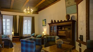A cozy living room with a sofa, armchairs, a wooden coffee table, and a television. - Bernardinu B&B House (Vilnius)