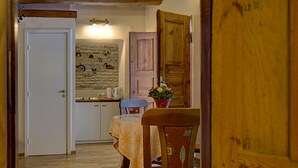 A cozy kitchen with a brick wall, wooden cabinets, and a dining area with a table and chairs. - Bernardinu B&B House (Vilnius)