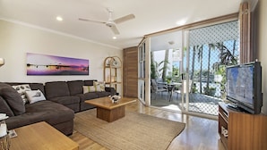 A modern living room with a sofa, coffee table, and TV. - Portside Noosa Waters (Noosaville)