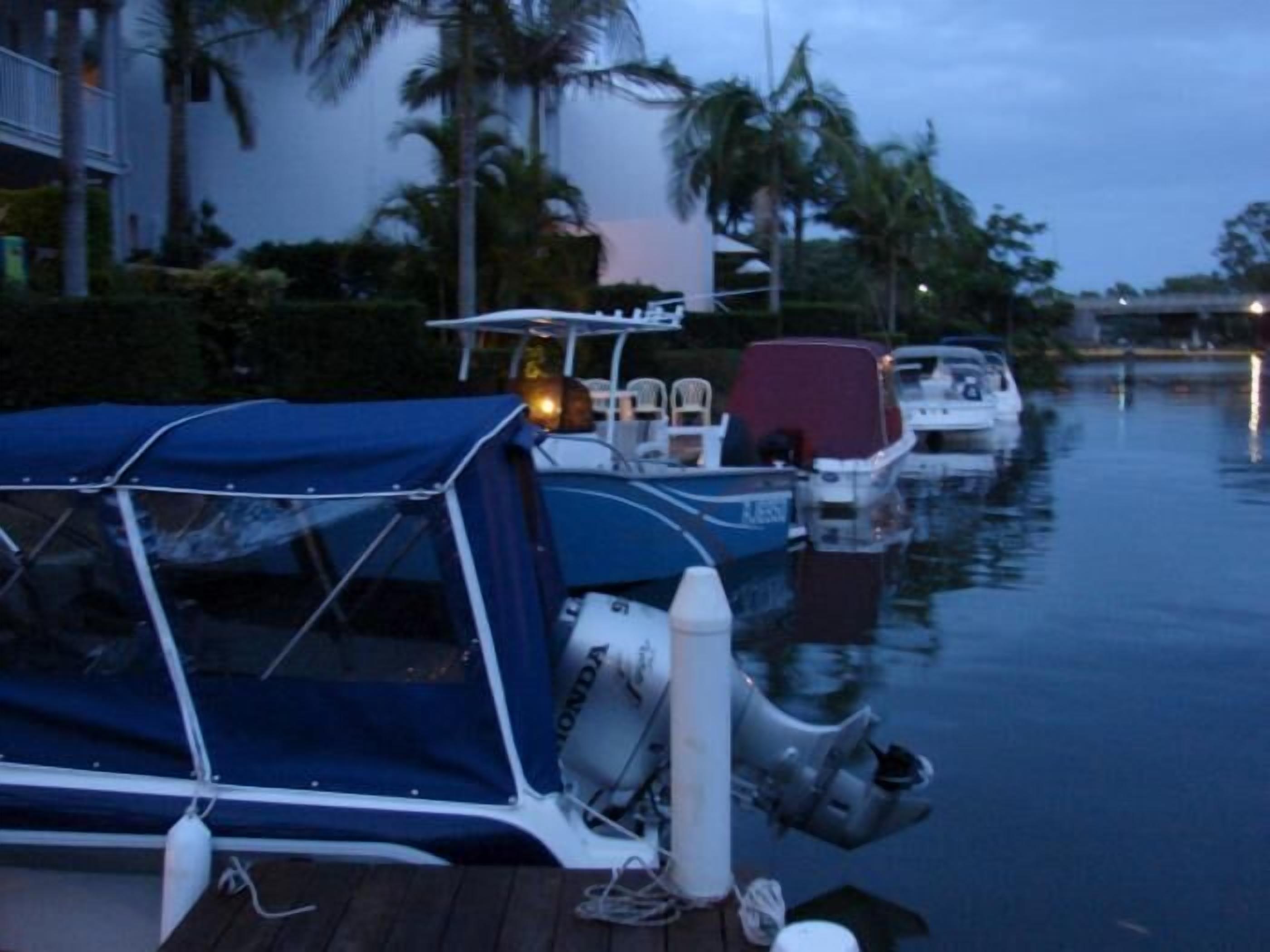 A boat docked at a marina with a covered seating area and a white cabin.