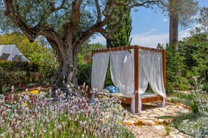 A garden with a wooden canopy bed surrounded by various plants and flowers. - Quinta Bonita Luxury Boutique Hotel (Lagos)