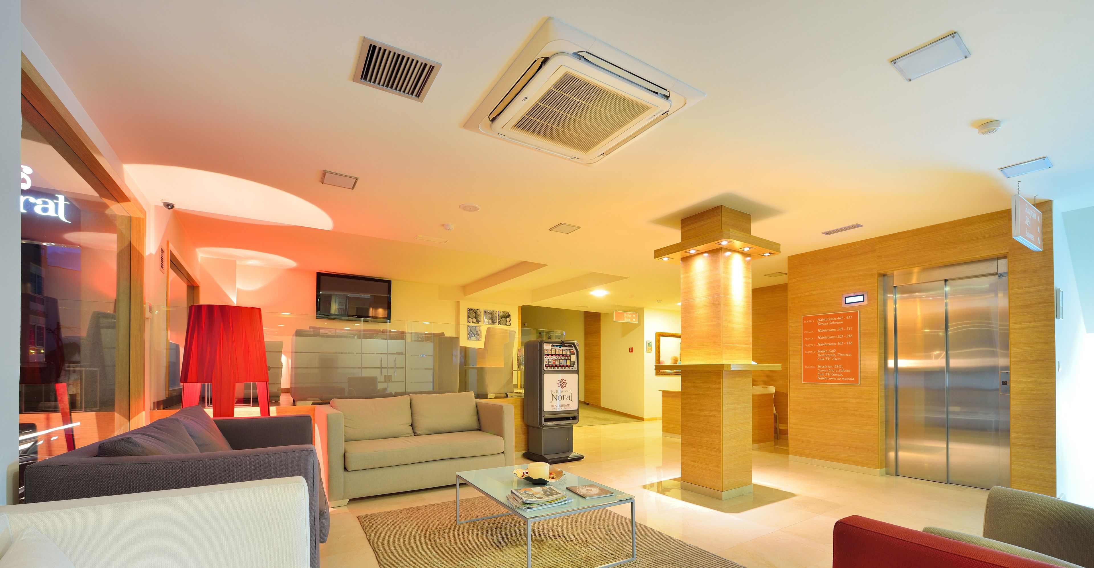 En moderne hotellobby med reception, sofa, sofabord og elevator.