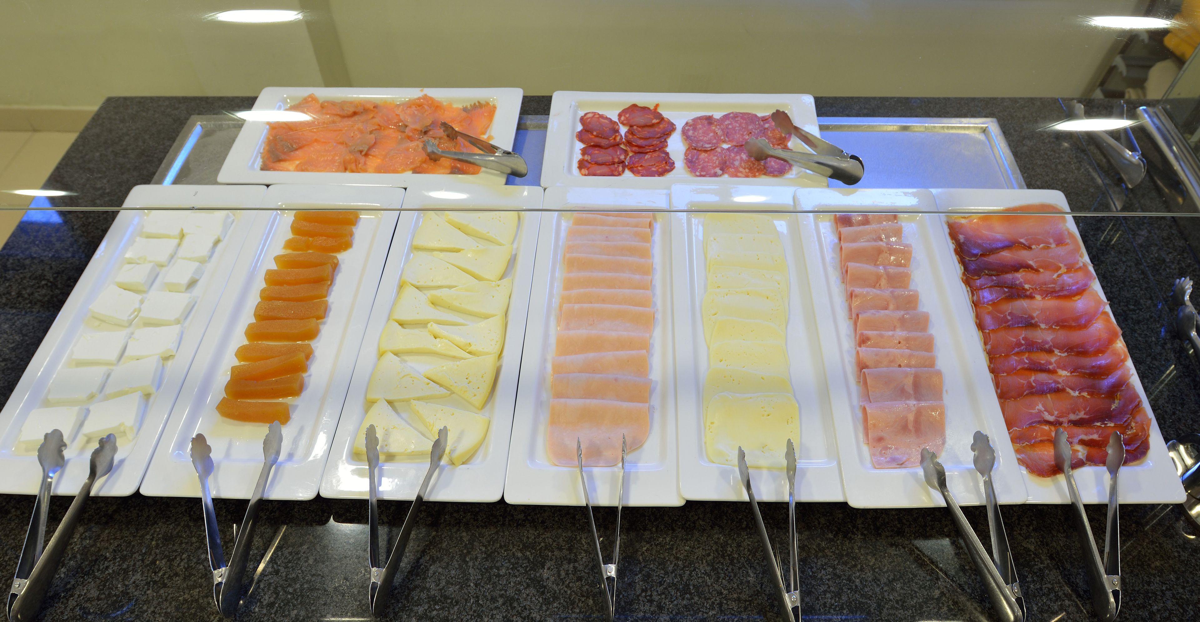 A buffet with various food items including meats, cheeses, and other prepared dishes.