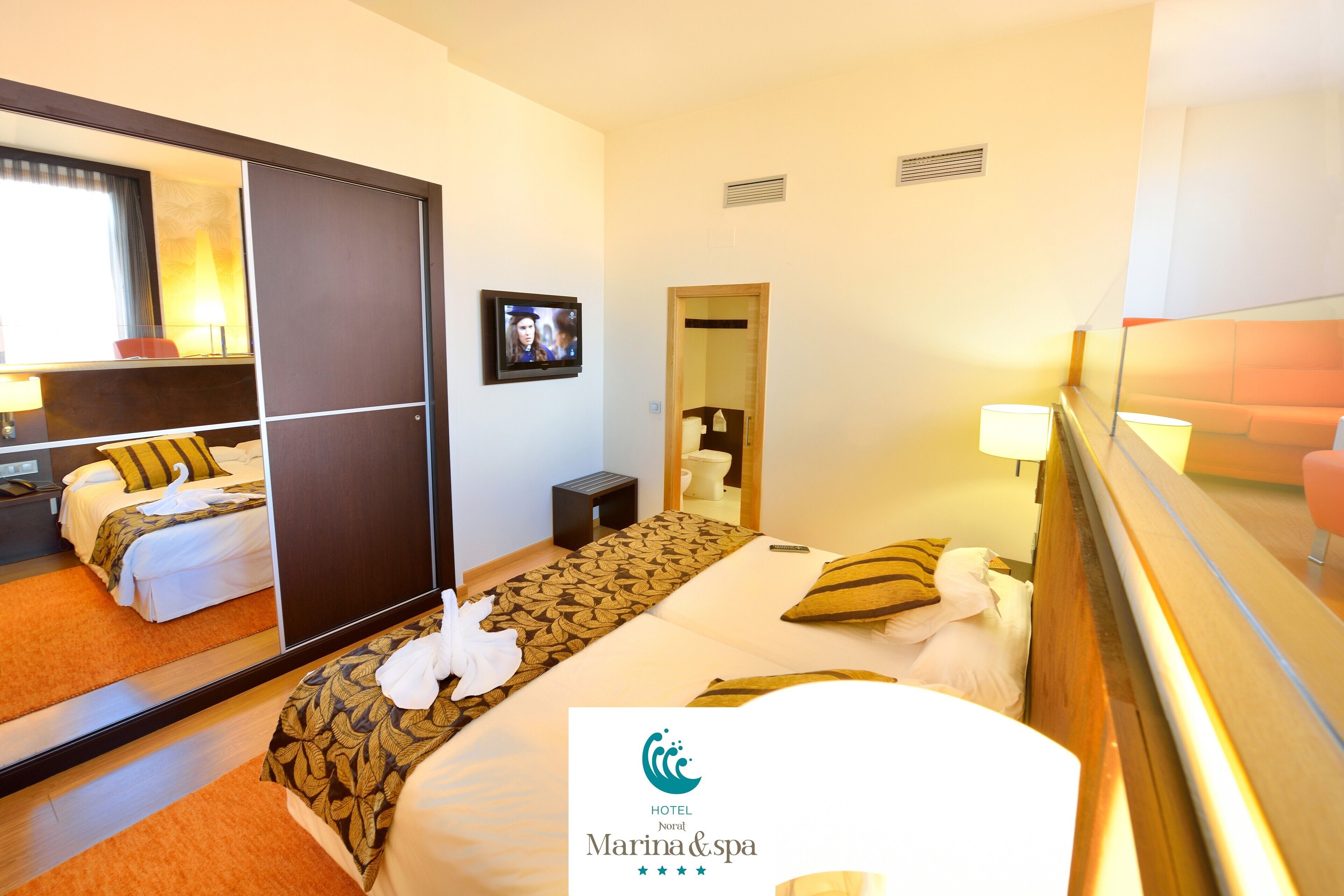 Ein Hotelzimmer mit einem Bett, einem Schreibtisch, einem Sessel, einem Spiegel und einem Fernseher.