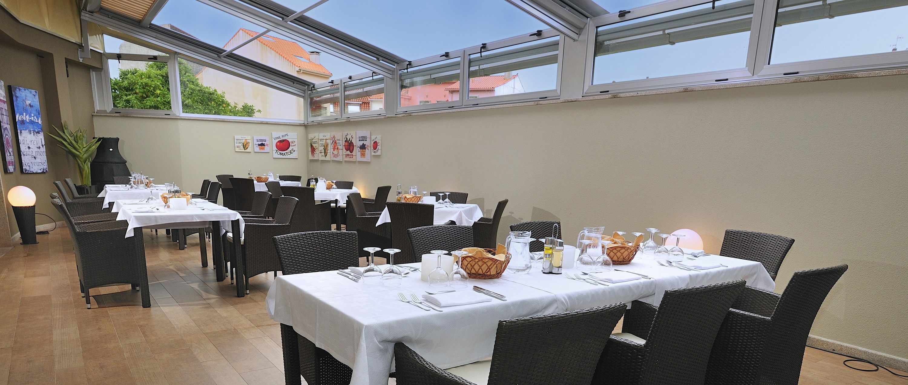 A restaurant with multiple tables set for dining, featuring wicker chairs and white tablecloths.