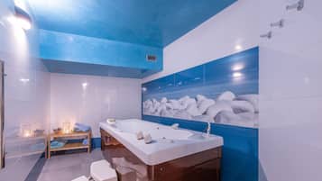 Un baño moderno con una bañera grande, un estante de madera con toallas y un inodoro de pared.