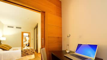 Una habitación de hotel con una cama, un escritorio con una computadora portátil, un espejo y un armario de madera.