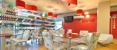 Un restaurante con una estantería de vinos, sillas y una mesa.