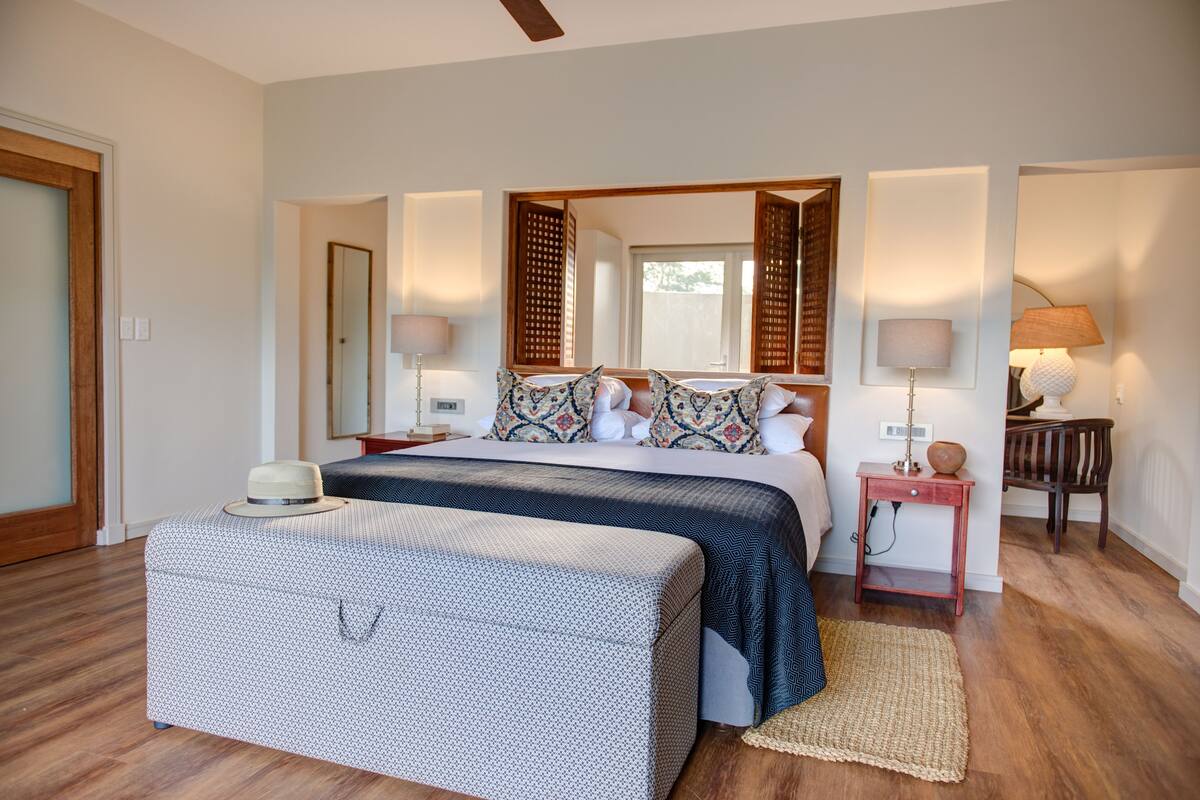 A bedroom with a bed, bedside tables, a mirror, and a suitcase.