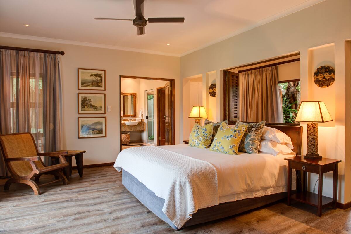 A bedroom with a bed, two nightstands, a chair, and a ceiling fan.