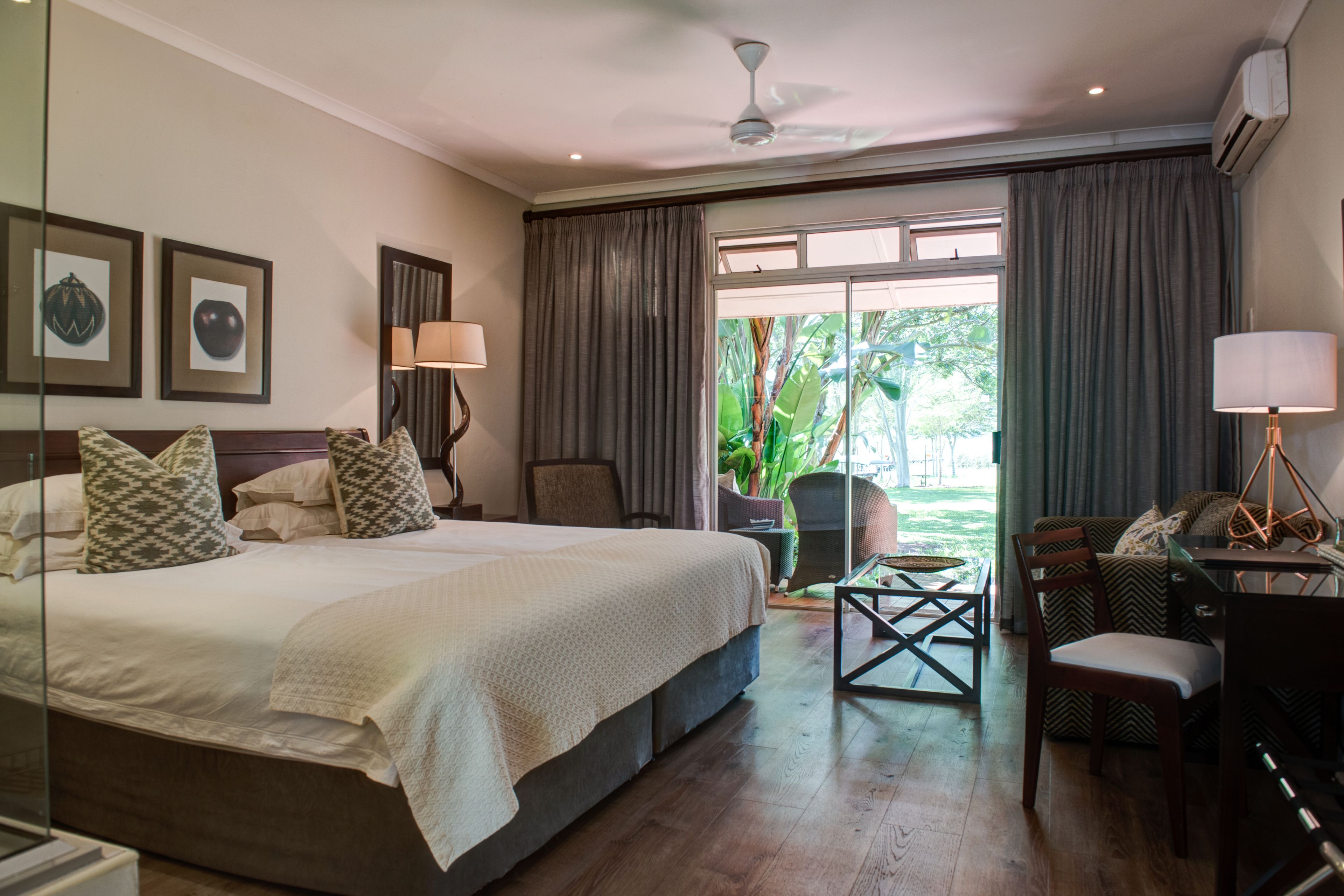 A hotel room with a large bed, a desk, a chair, and a view of the outdoors.