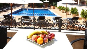 A poolside area with lounge chairs and umbrellas, a fruit plate on a table, and a pool in the background. - Apartamentos Jade - Adults Only +16 (Palma de Mallorca)