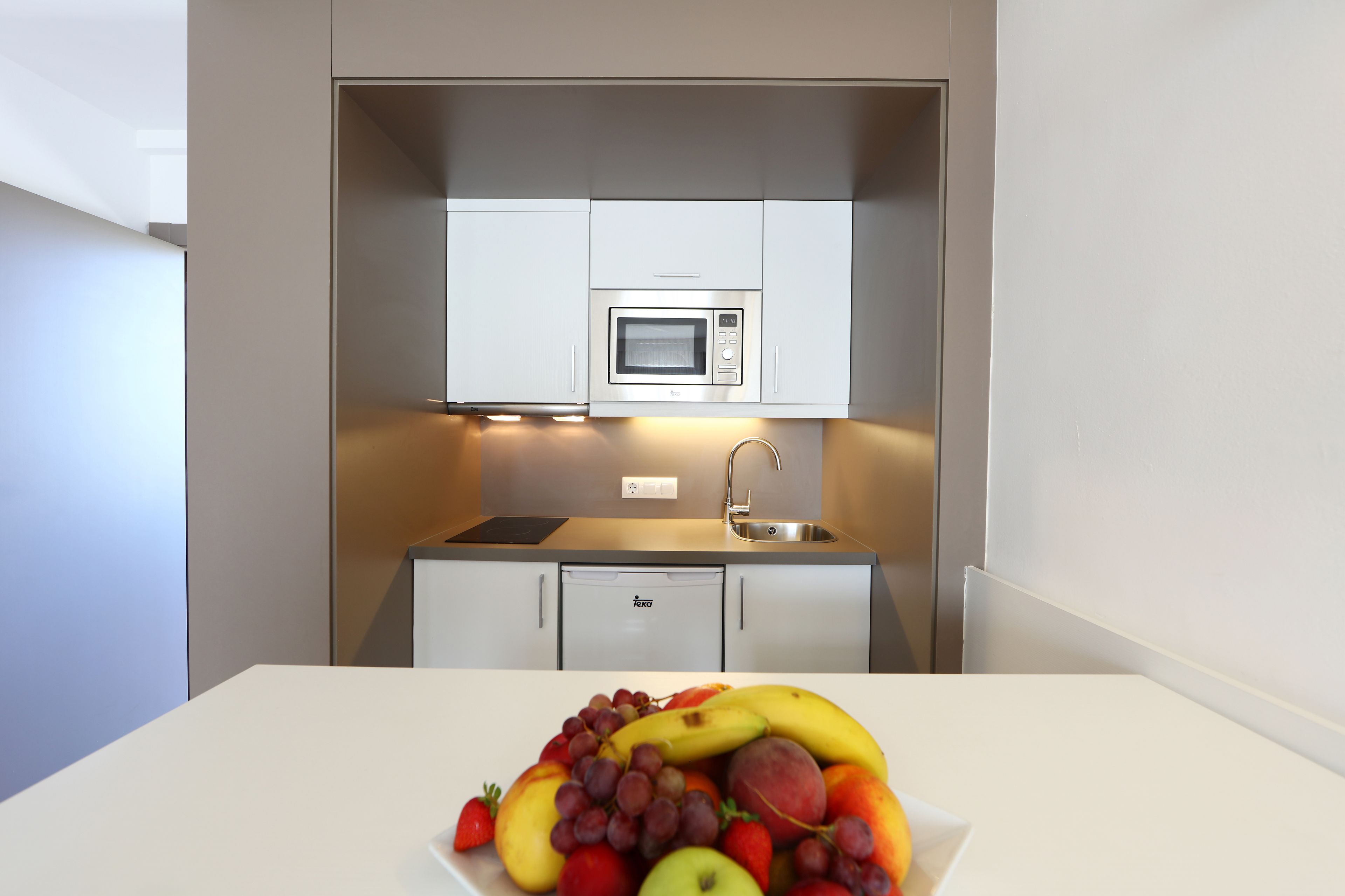 Une petite cuisine équipée d’un four à micro-ondes, d’un évier et de placards de rangement.