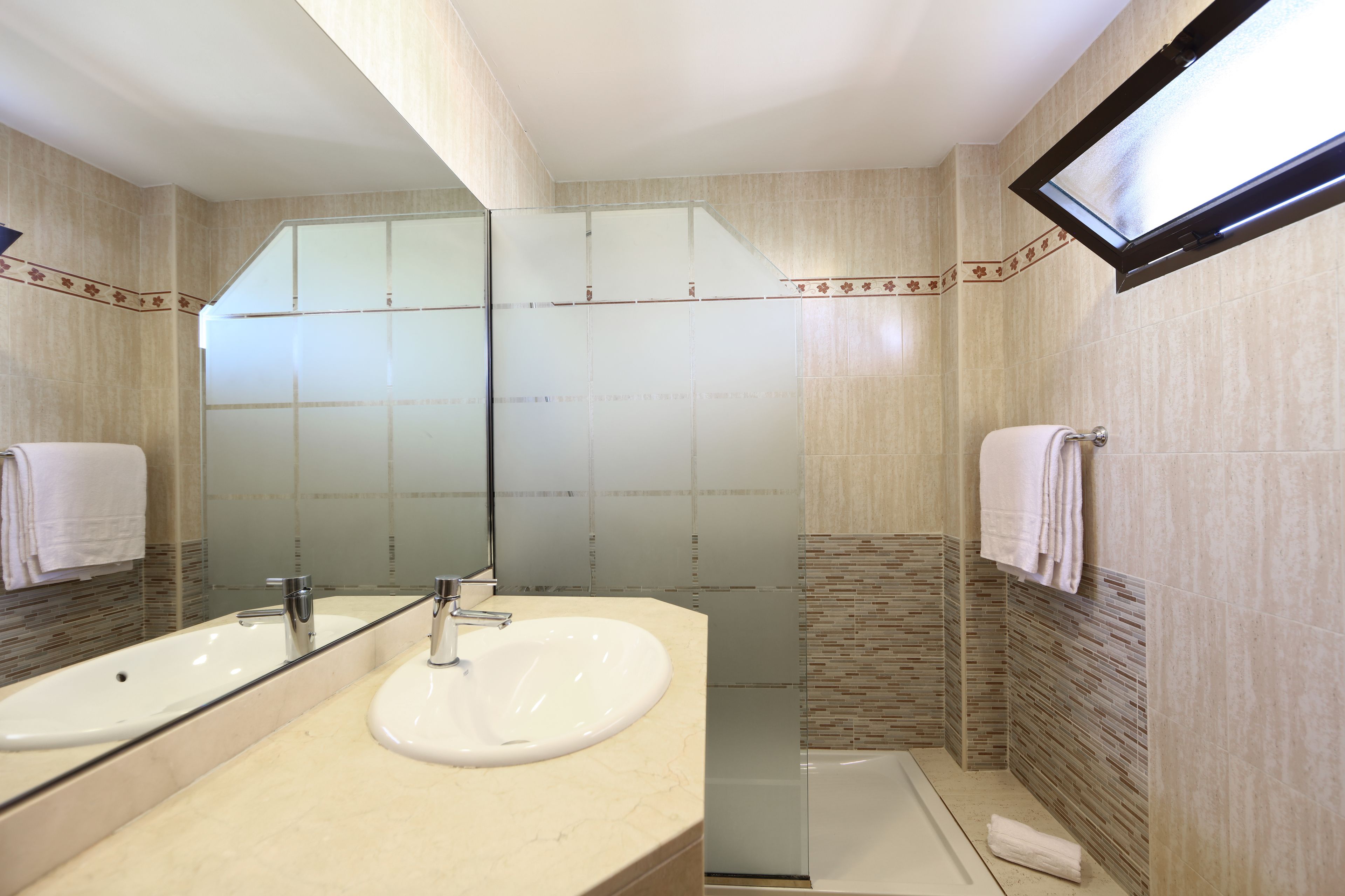 A bathroom with two sinks, a large mirror, and a shower area.