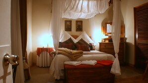 A bedroom with a canopy bed, a bedside table, a nightstand, and a mirror. - Knysna Manor House (Knysna)
