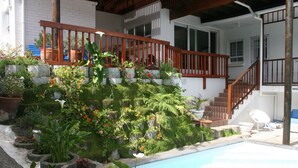A swimming pool with a wooden deck and a staircase leading to a second floor. - Knysna Manor House (Knysna)