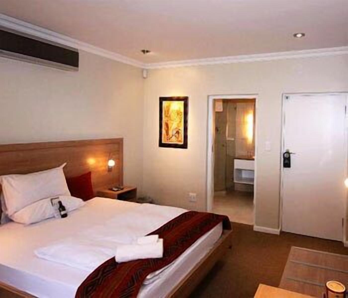 Habitació d'hotel amb llit, taulell de nit i un quadre a la paret.