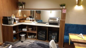 A kitchenette with a coffee maker, toaster, and storage shelves.