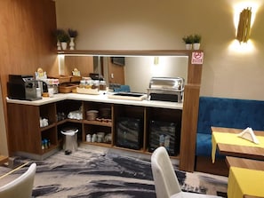 A kitchenette with a coffee maker, toaster, and storage shelves.