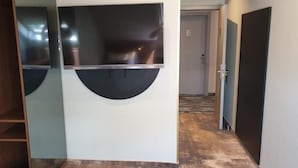 A hallway with a modern design, featuring a wall-mounted TV and a door leading to another room.