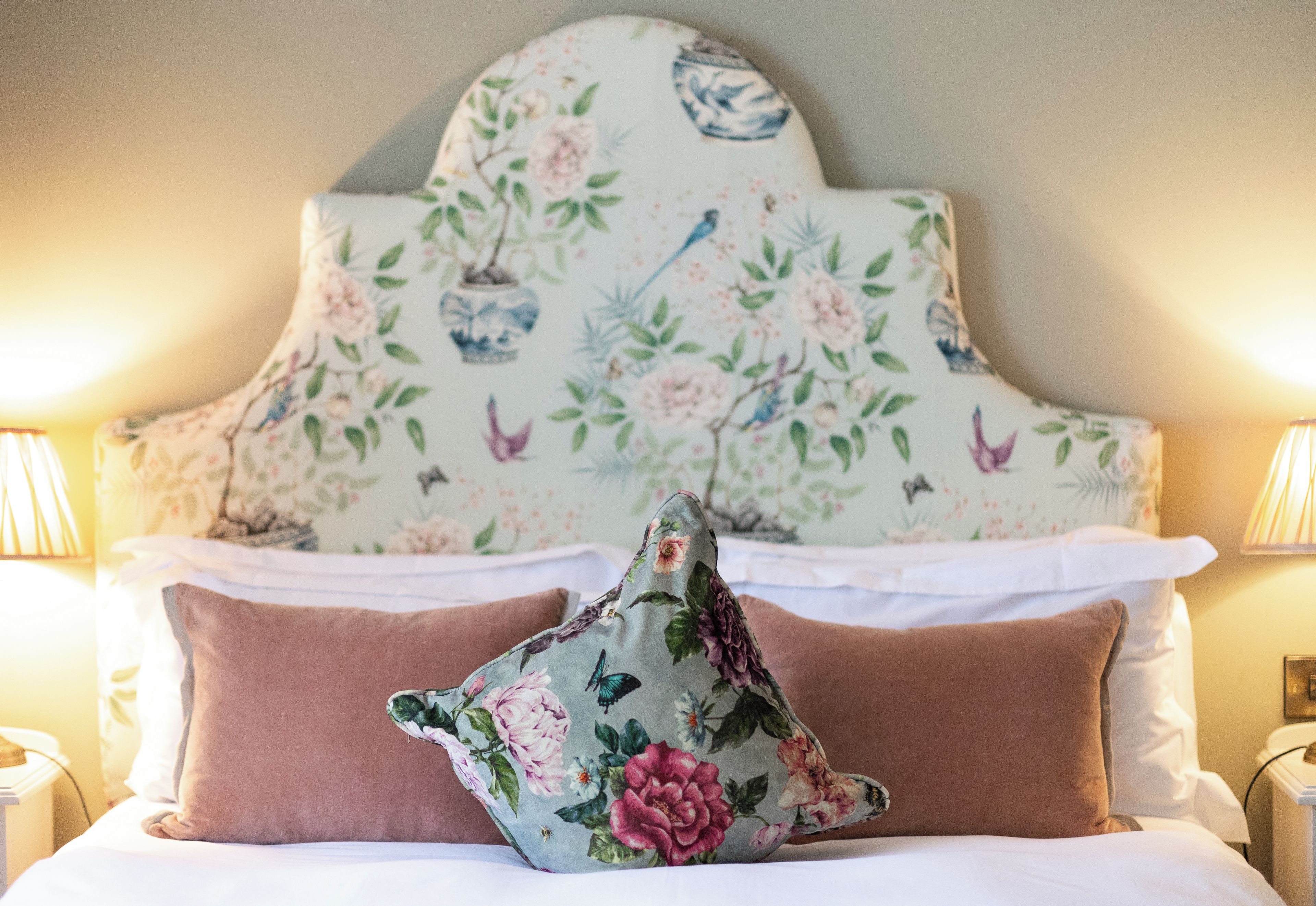 A bed with floral-patterned pillows and a matching headboard.