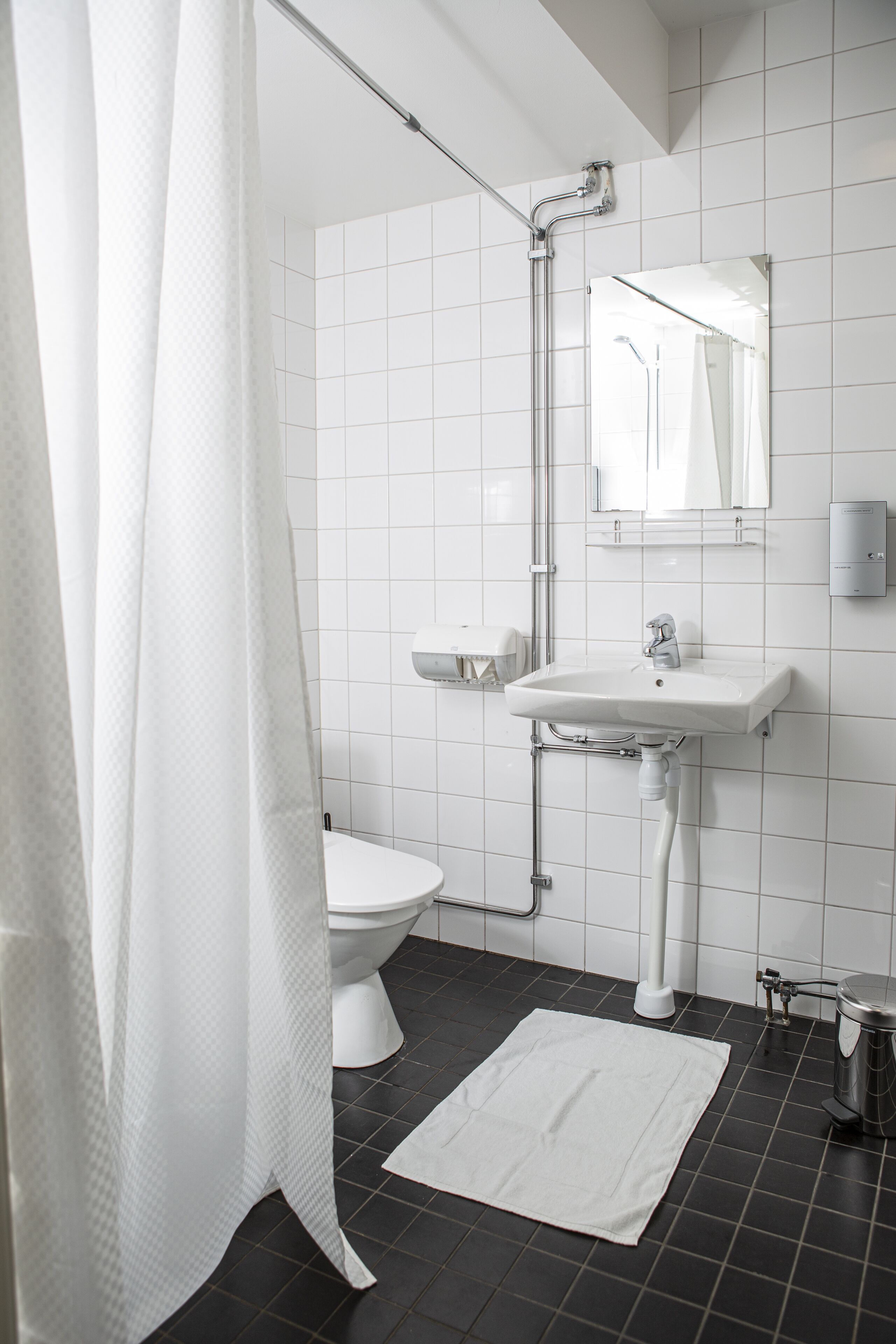 A modern bathroom with a white toilet, a sink with a mirror above it, and a shower area with a curtain.