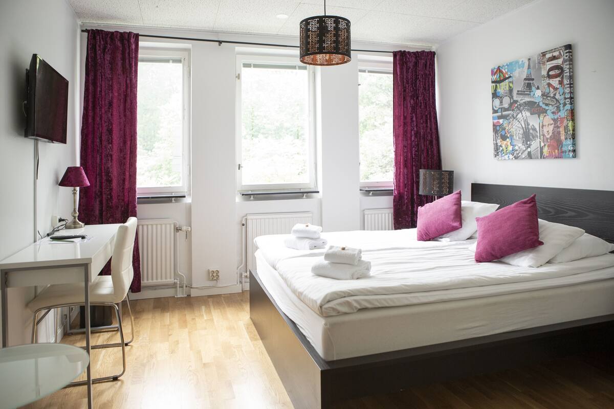 A modern hotel room with a bed, a desk, and a chair.