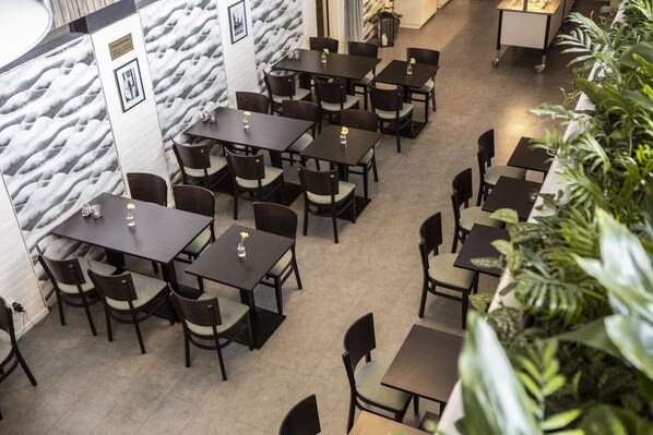 Un restaurante con varias mesas y sillas dispuestas en un espacio amplio.
