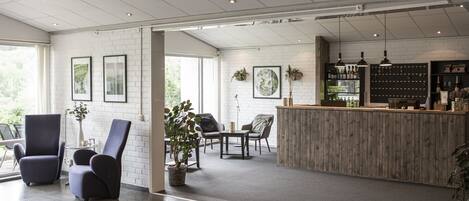 A spacious lobby with a reception desk, seating area, and large windows.