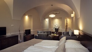 Habitación de hotel con una cama grande, dos sillones, un sofá, un televisor y un escritorio con lámpara.