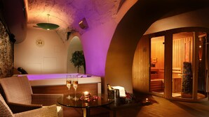 Un ambiente interior acogedor con mobiliario de mimbre, una mesa de vidrio y una zona de sauna de madera.