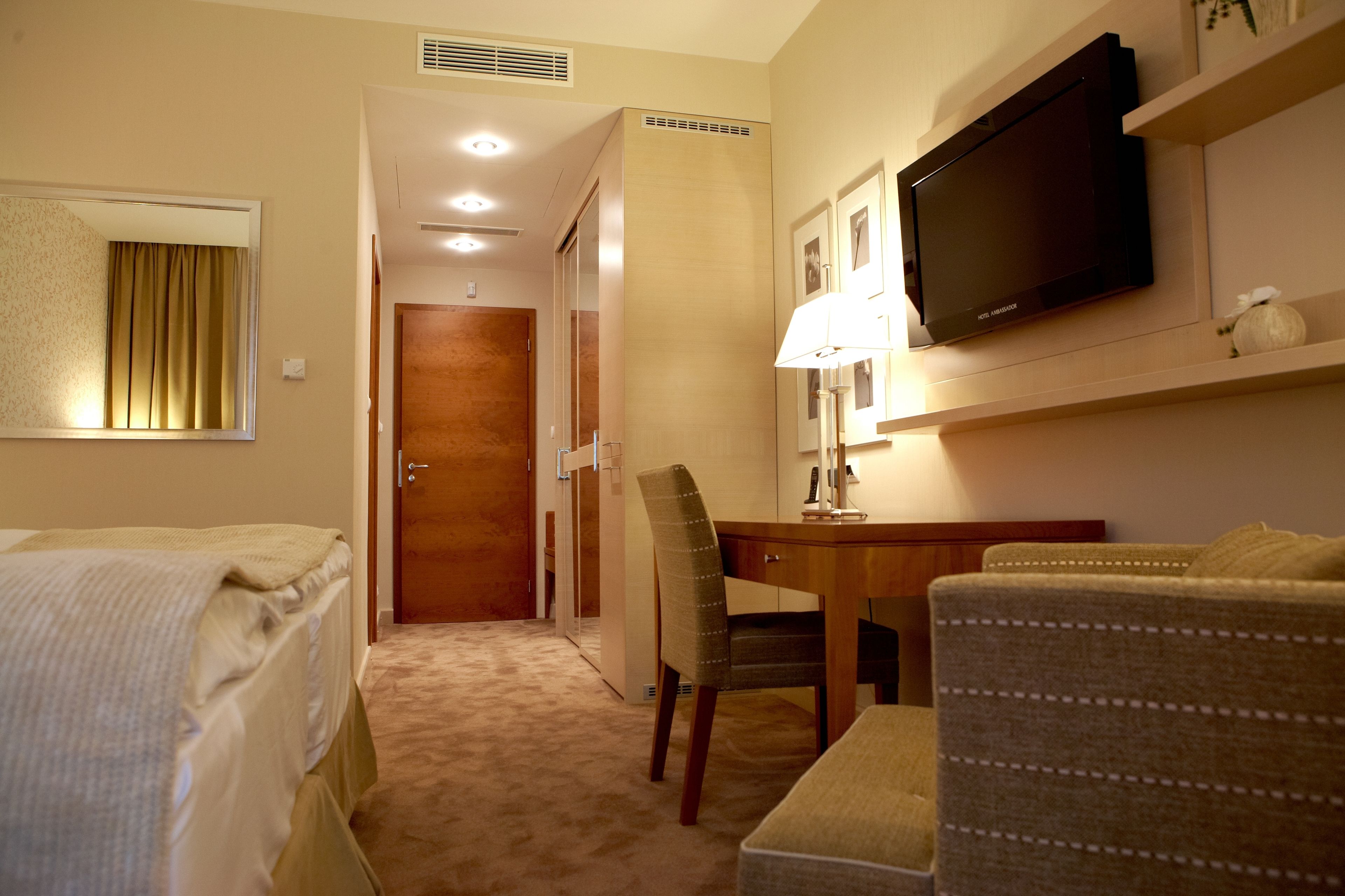 A hotel room with a bed, a desk, a television, and a chair.