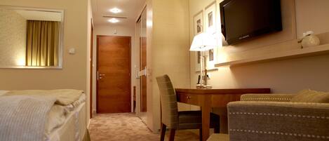 A hotel room with a bed, a desk, a television, and a chair.