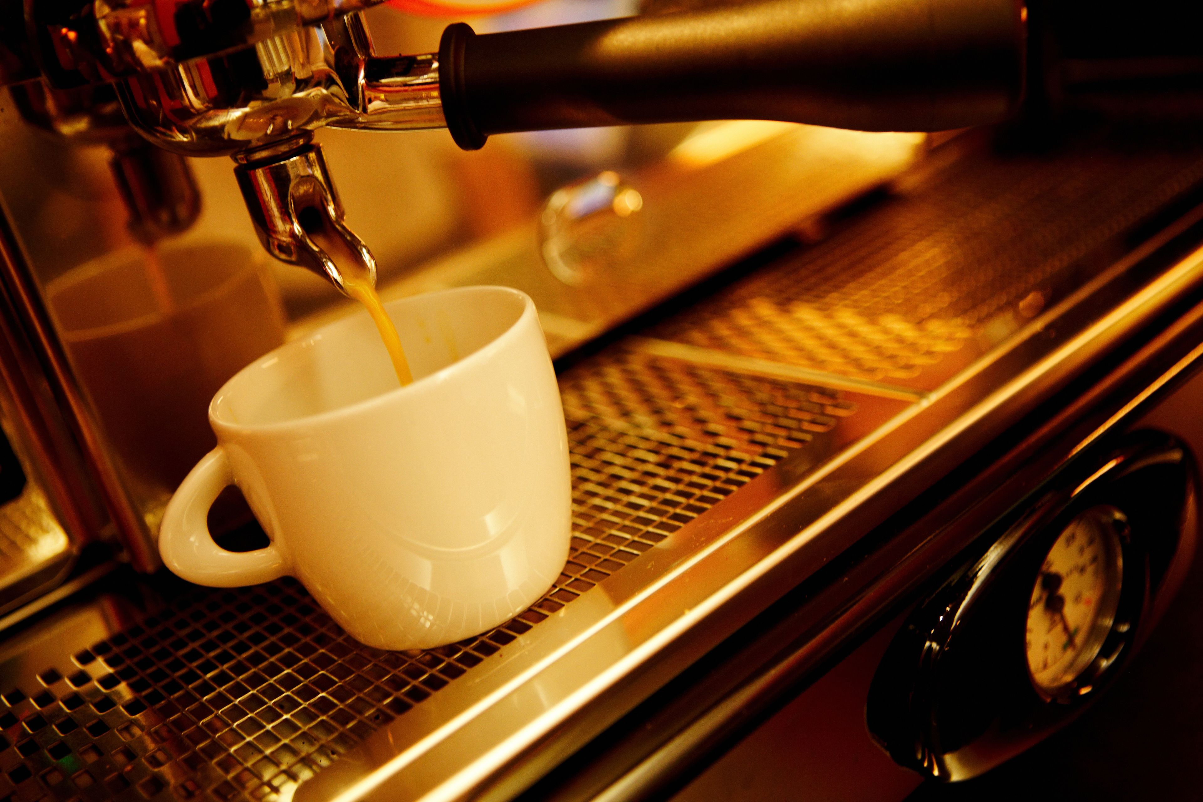Une machine à café verse du café dans une tasse blanche.