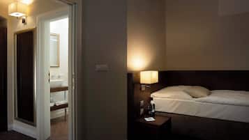 A hotel room with a bed, bedside table, and a bathroom visible through an open door.