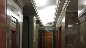 Un pasillo con paredes de mármol, suelo de baldosas y un ascensor.