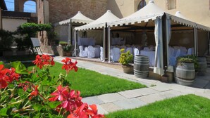 A courtyard with a brick building, white tents, and potted plants. - Relais Palazzo Paleologi - Secolo XIV (Lu e Cuccaro Monferrato)